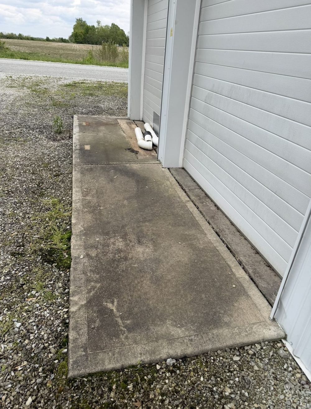 Stained gray concrete walkway with moss and dirt before pressure washing
